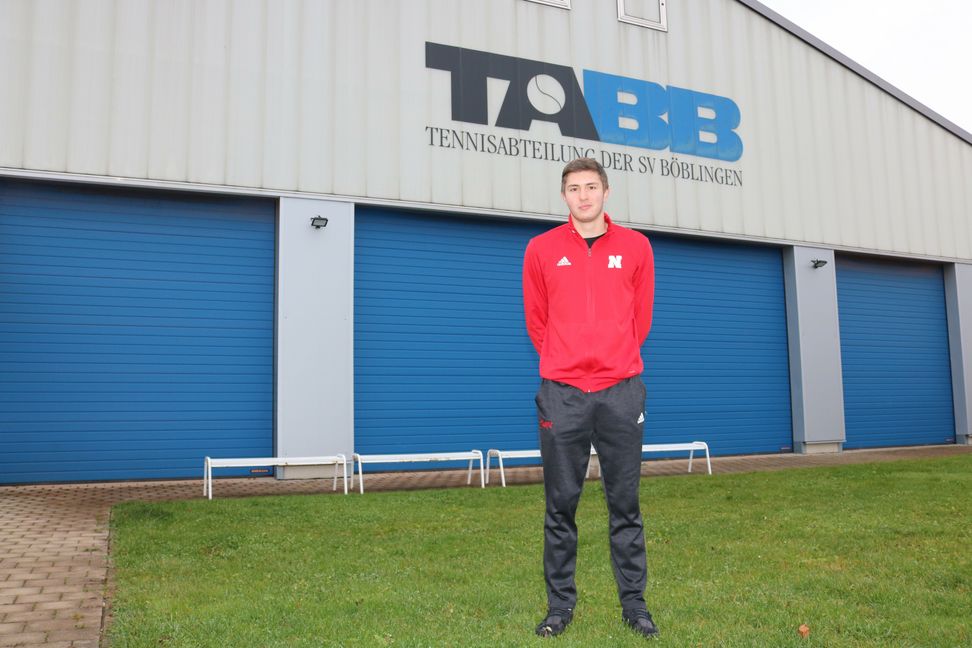 Nic Wiedenhorn im Trainingspulli der Universität von Nebraska vor der TABB-Tennishalle. Die meisten Bälle schlägt der Böblinger allerdings auf amerikanischen Betonböden über das Netz.  Bild: Bilaniuk