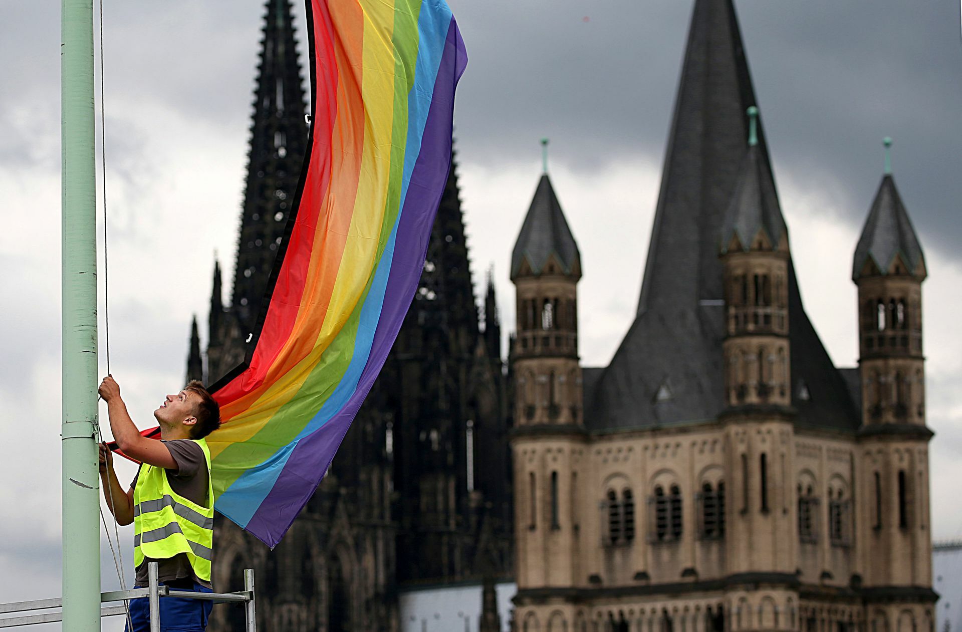 Auf Halbmast? Regenbogenfahne vor kirchlichem Hintergrund. Foto: dpa/Oliver Berg