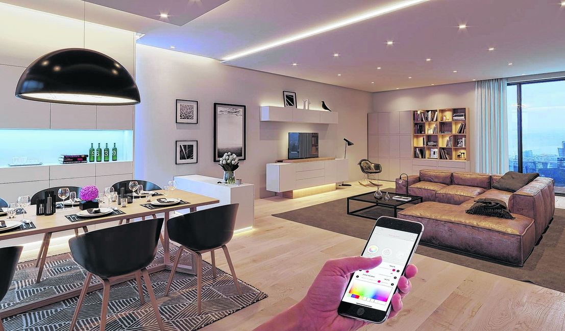 Ess- und Wohnzimmer, ausgestattet mit dem LED-Leuchtensystem Loox von Häfele. Die verschiedenen Lichtszenarien und der versenkbare Bildschirm werden per Häfele Connect-App mit dem Smartphone gesteuert.