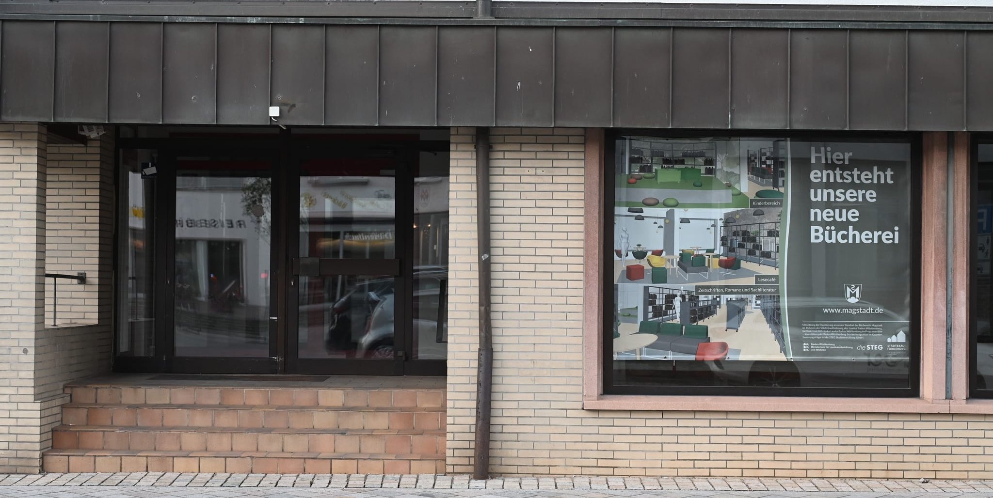 Zu den Gestaltungsvorschlägen der Architektengruppe KWP gehört auch, den bisherigen Eingang an die Stelle des Schaufensters zu verlegen, in dem derzeit das Plakat „Hier entsteht unsere neue Bücherei“ hängt. Bild: Reichert