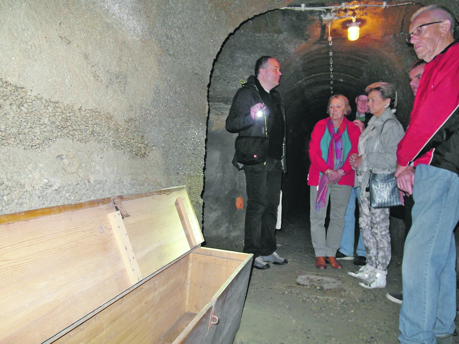 Matthias Witschel führt eine Besuchergruppe durch den Böblinger Schlossbergstollen. Eine Sitztruhe ist das einzige Möbelstück. Bild: Staber