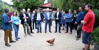Landwirtschaft hautnah erlebt: Als die Gäste samt Bundeslandwirtschaftsminister Alois Rainer (Bildmitte) vor der Gärtnerei Station machten, spazierte ein Huhn vorbei und ließ sich auch von den hochrangigen Gästen nicht aus der Ruhe bringen.