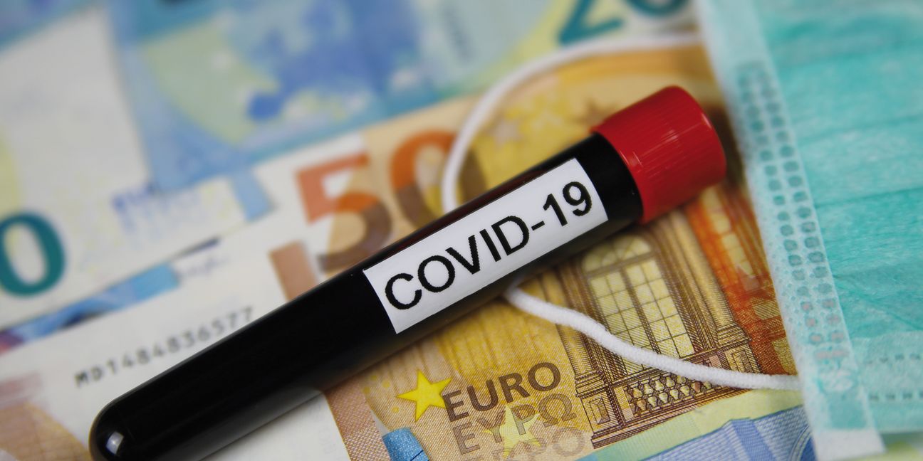Corona virus uncertain consequential costs concept symbol: closeup of isolated blood sample vial on euro paper money bank notes und surgical mask