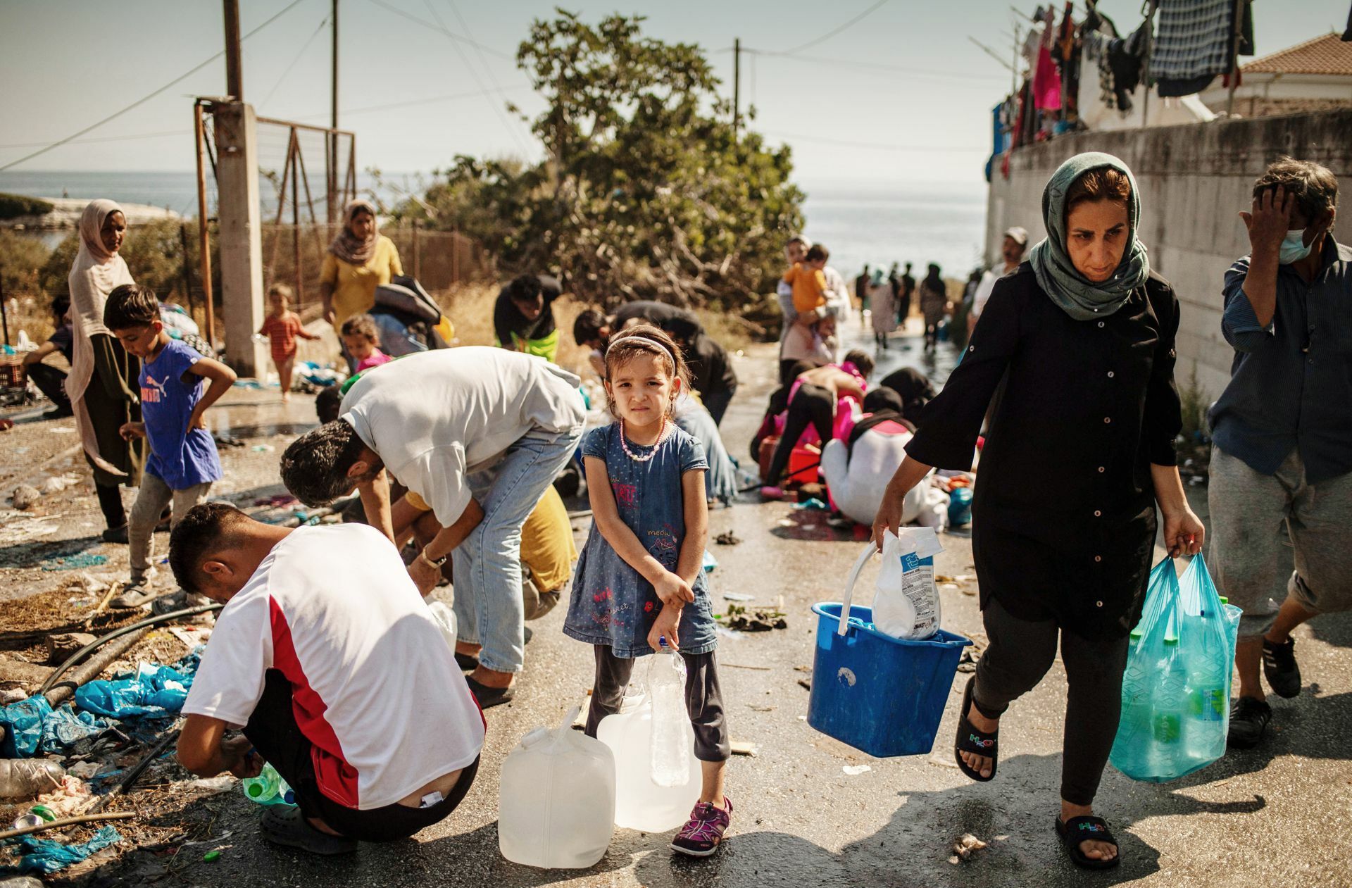 Ein Mädchen wartet darauf, ihre Wasserflasche auf Lesbos wieder aufzufüllen.