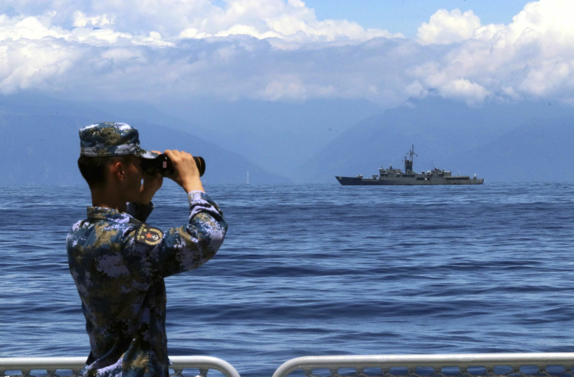 Ein chinesischer Soldat beobachtet eine taiwanesische Fregatte.