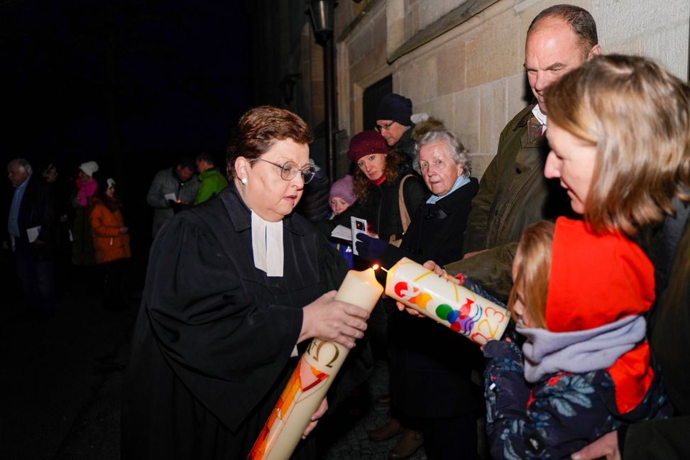 Vor dem Entzünden am Osterfeuer werden die Osterkerzen von Pfarrerin Gerlinde Feine gesegnet, dann breitet sich das Licht weiter aus. Bild: Dettenmeyer
