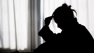 Silhouette einer Frau vor einer hellen Fensterfront