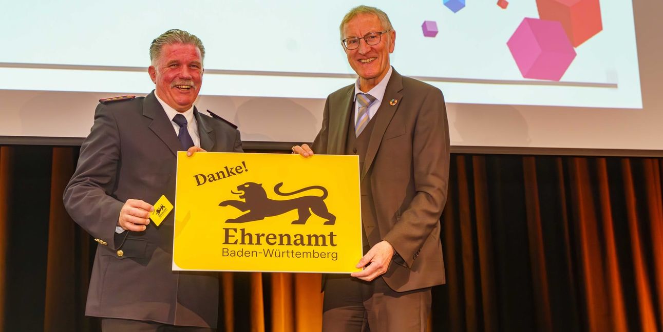 Landrat Roland Bernhard (rechts) übergibt die erste Ehrenamtskarte an den Vorsitzenden des Kreisfeuerwehrverbandes Böblingen Markus Priesching. Bild: Dettenmeyer