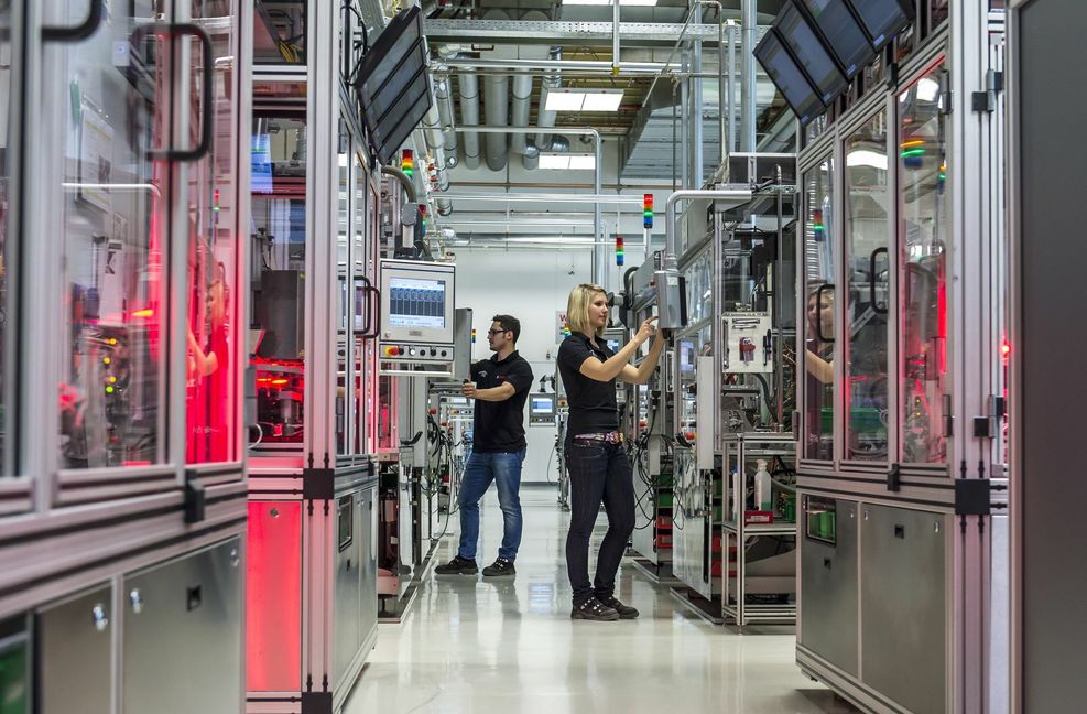 Bosch-Beschäftigte  verdienen je nach Funktion und Hierarchiestufe nach dem Metall-Tarifvertrag oder erhalten eine außertarifliche Vergütung. Das Bild zeigt zwei Beschäftigte, die an Maschinen zur Herstellung von Ventilkörpern für Benzin-Direkteinspritzsysteme arbeiten. Foto: dpa/Daniel Maurer