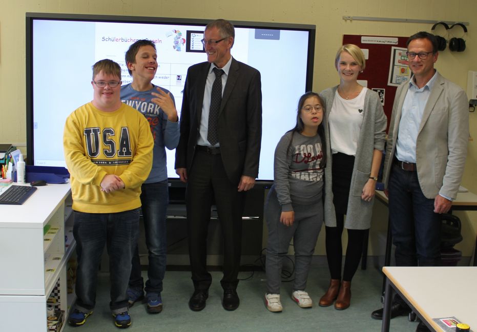 Landrat Roland Bernhard, Schulleiter Albrecht Gall und die Lehrerin Nadine Redeker mit Schülern vor dem Interaktiven Display.