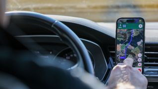 So ist es derzeit erlaubt: Das Handy steckt in der Halterung und wird nur kurz vom Fahrer beachtet. (Symbolbild)