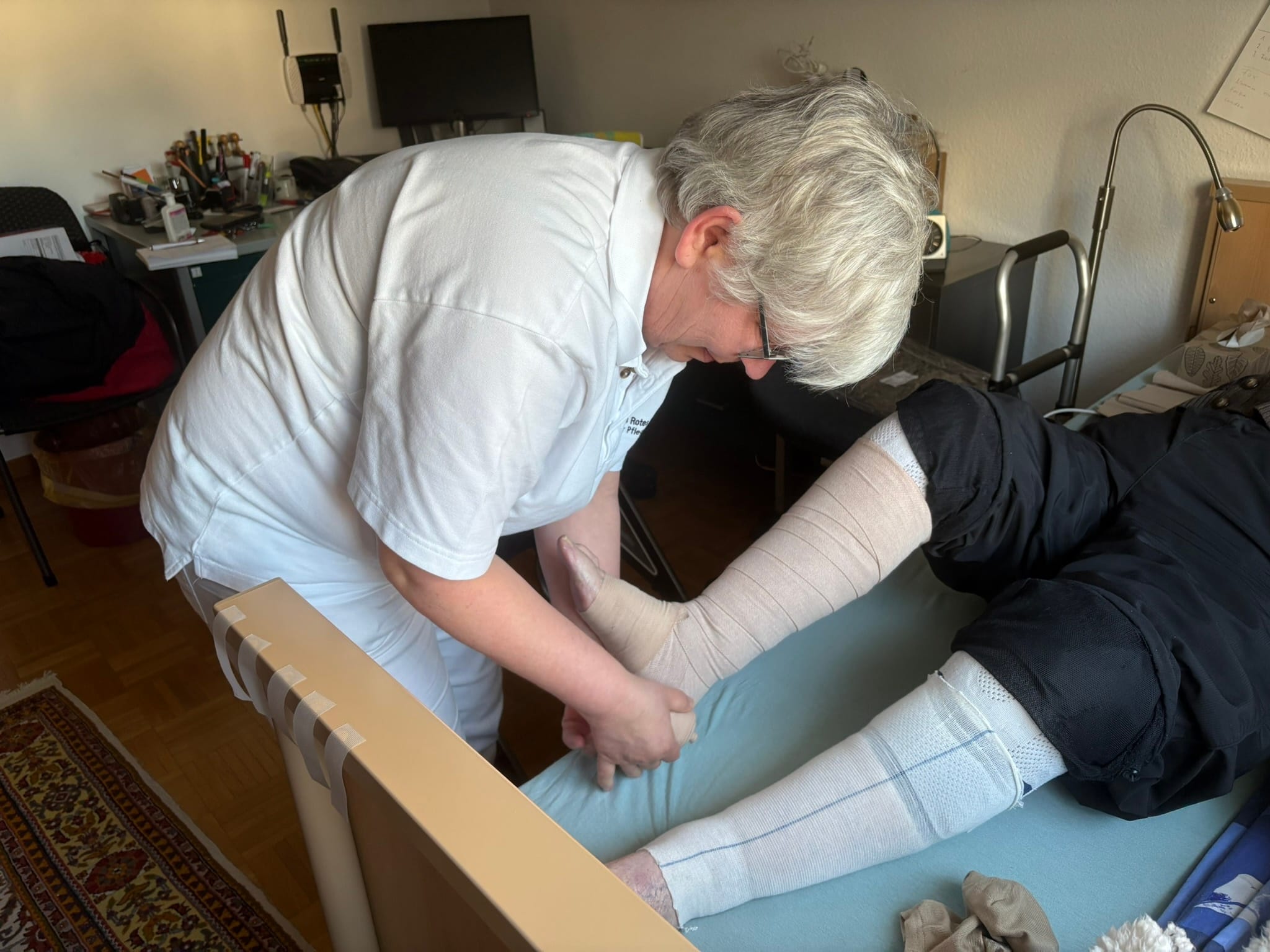 Martina Caspari kümmert sich beim Hausbesuch um die Beine einer Kundin.