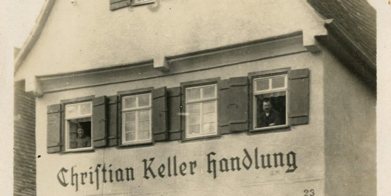 Das Wohn- und Geschäftshaus von 1923: Karoline (links) und Friedrich Christian Keller schauen aus den Fenstern.