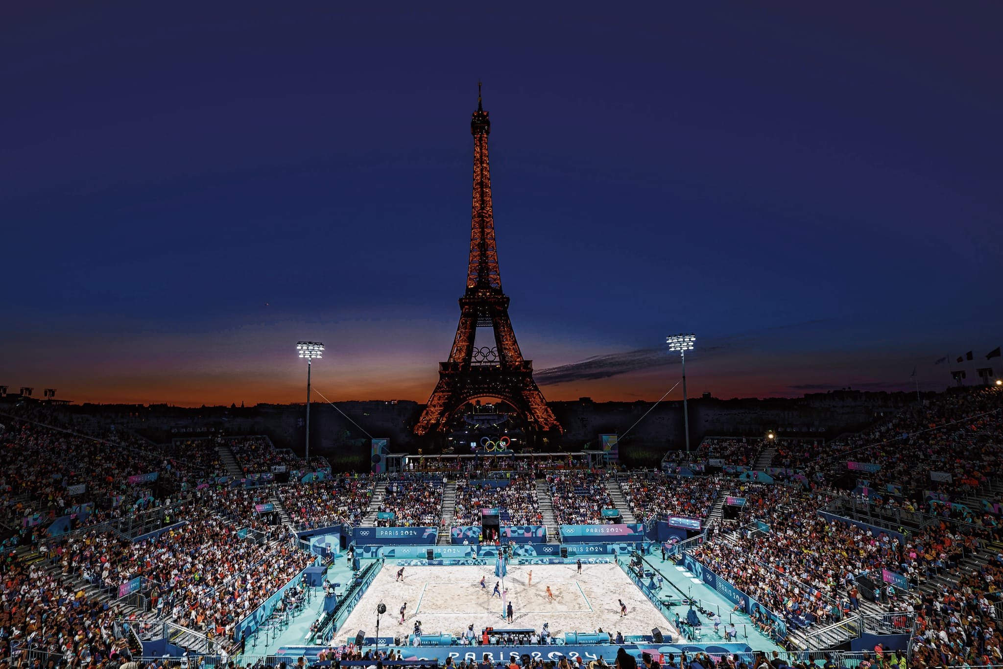 Ein unglaublich stimmungsvolles Bild: Der Beachvolleyball-Wettbewerb bei den olympischen Spielen 2024 im Abendlicht von Paris vor dem Eiffelturm.