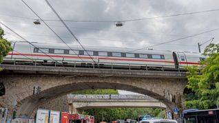 Einsatzkräfte von Polizei und Feuerwehr stehen an einer Eisenbahnunterführung am Bergischen Ring, auf der ein ICE liegengeblieben ist.