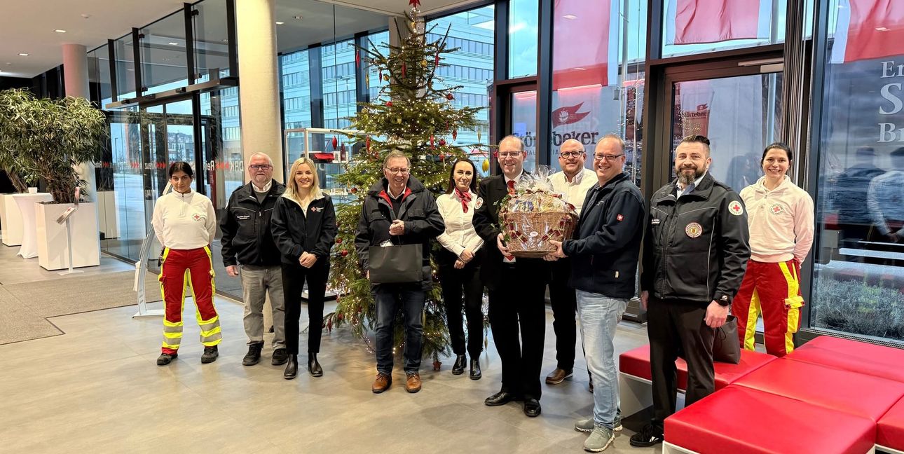 Das Team der Heilig-Abend-Tour in der Rettungswache auf dem Flugfeld mit DRK-Präsident Michael Steindorfner (vor dem Baum), OB Dr. Bernd Vöhringer (am Korb links), Wolfgang Hesl (Kreisgeschäftsführer), Sonja Hein (stellvertretende Kreisgeschäftsführerin), Sven Peters (Rettungsdienstleiter), Vanessa Heni (Regionalleitung Süd, Altenpflegeheime) sowie Klaus-Dieter Grossnick (Bereichsleiter Rotkreuzdienste).