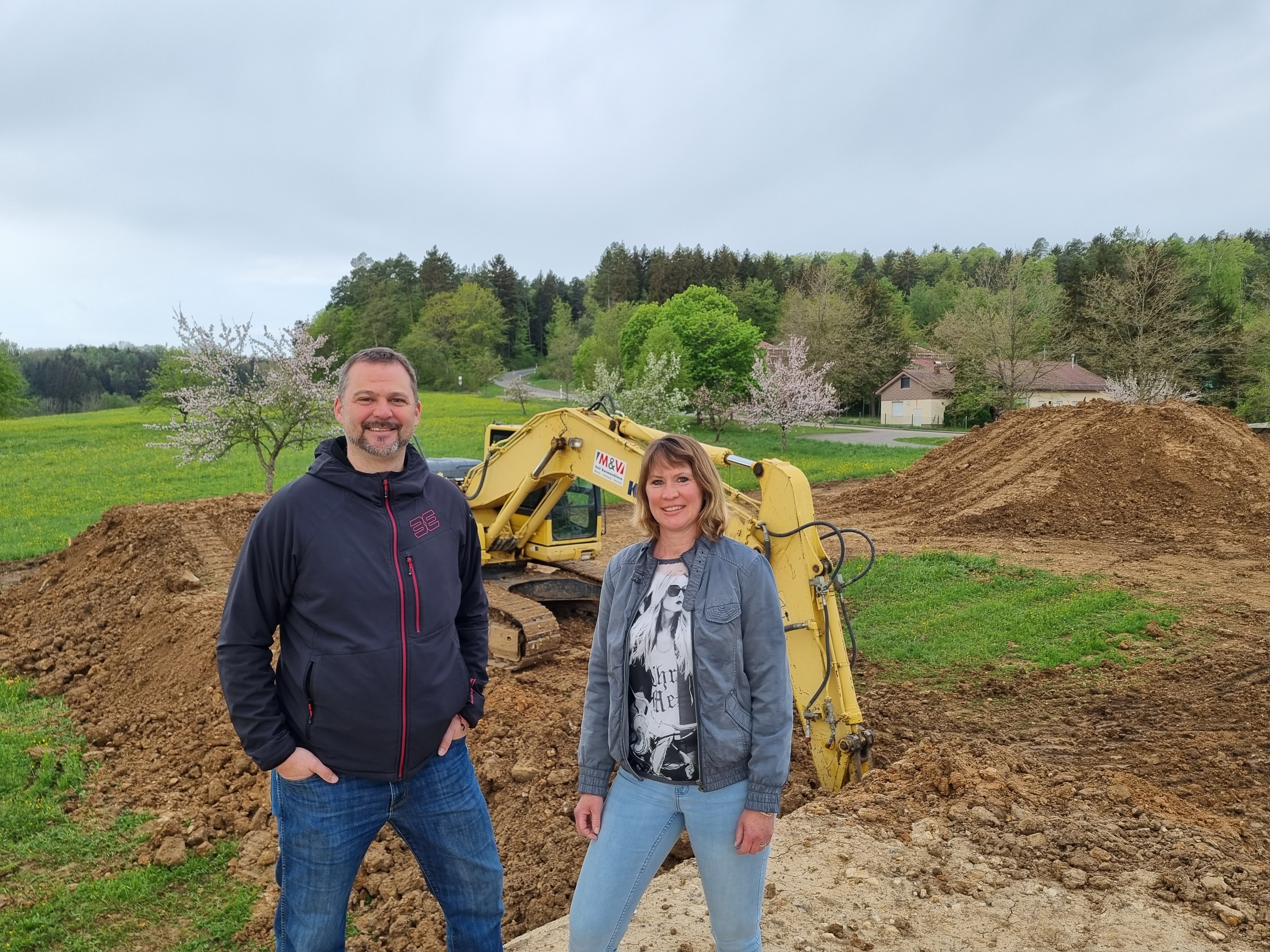 Marco Cartarius und Melanie Hahn stehen dort, wo zurzeit  mit Baggern ein Dirt-Park  gebaut wird, auf einem Erdhügel. Im Hintergrund befindet sich das Waldstück, in dem nächstes Jahr Mountainbike-Trails eingeweiht werden sollen. Bild: Hamann´´