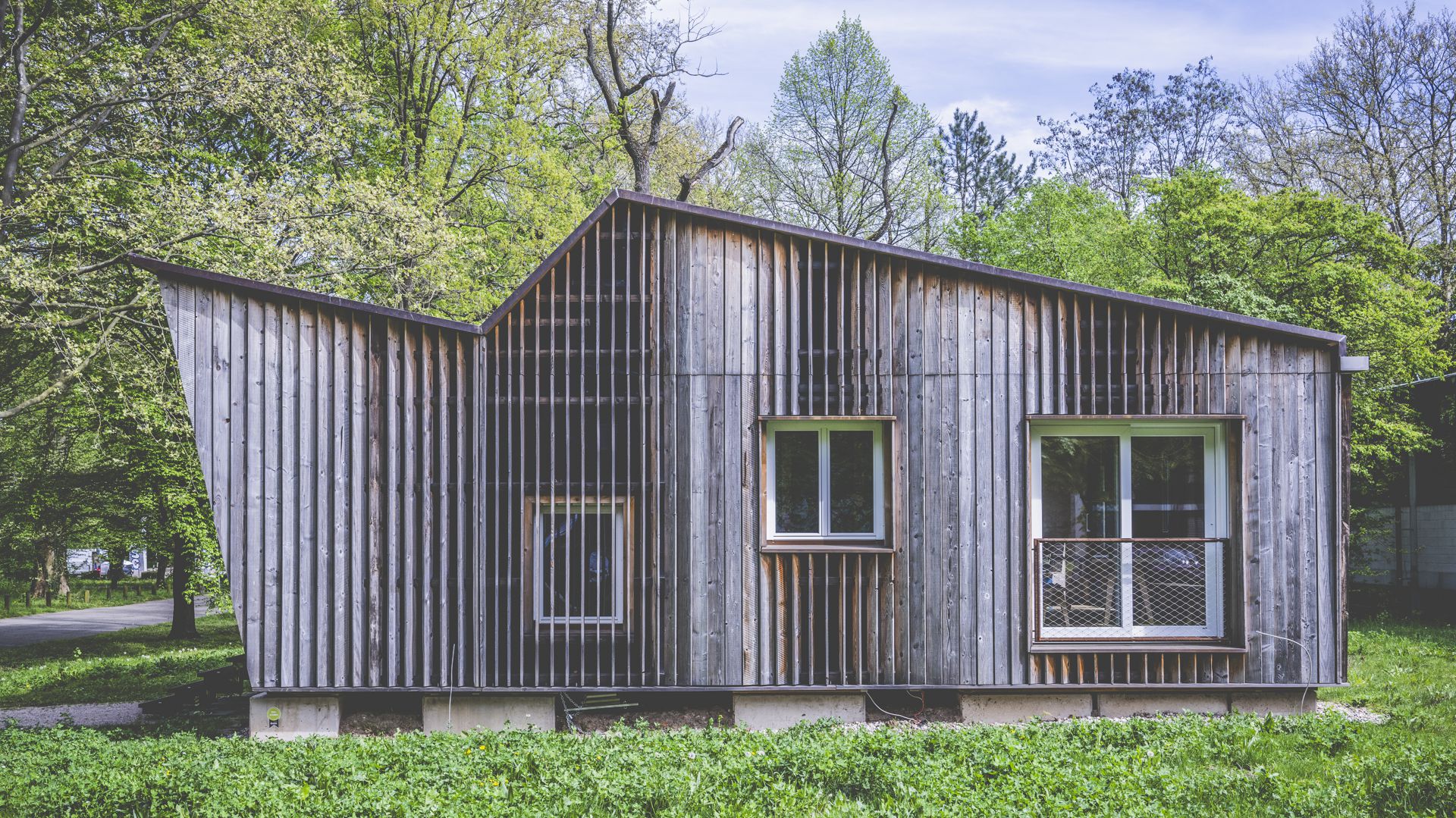 Die Fassade besteht aus schräg gestellten senkrechten Holzlamellen, genauer gesagt aus unbehandelten Brettern.