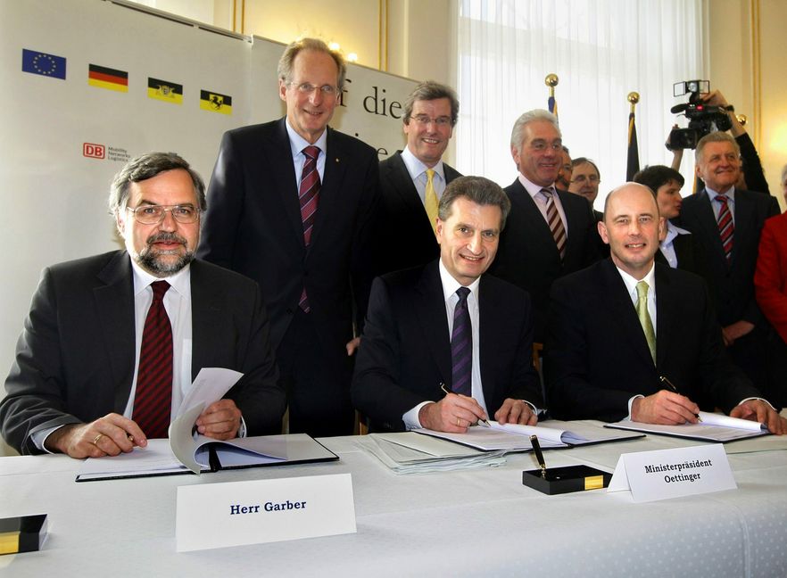Unterzeichnung des Finanzierungsvertrags für Stuttgart 21 im April 2009: Stefan Garber, Vorstand Infrastruktur der Deutschen Bahn, Günther Oettinger, damals Ministerpräsident von Baden-Württemberg, und der damalige Bundesverkehrsminister Wolfgang Tiefensee (vorne, von links). Über deren Schulter schauen Stuttgarts Oberbürgermeister Wolfgang Schuster und Regionalpräsident Thomas S. Bopp.