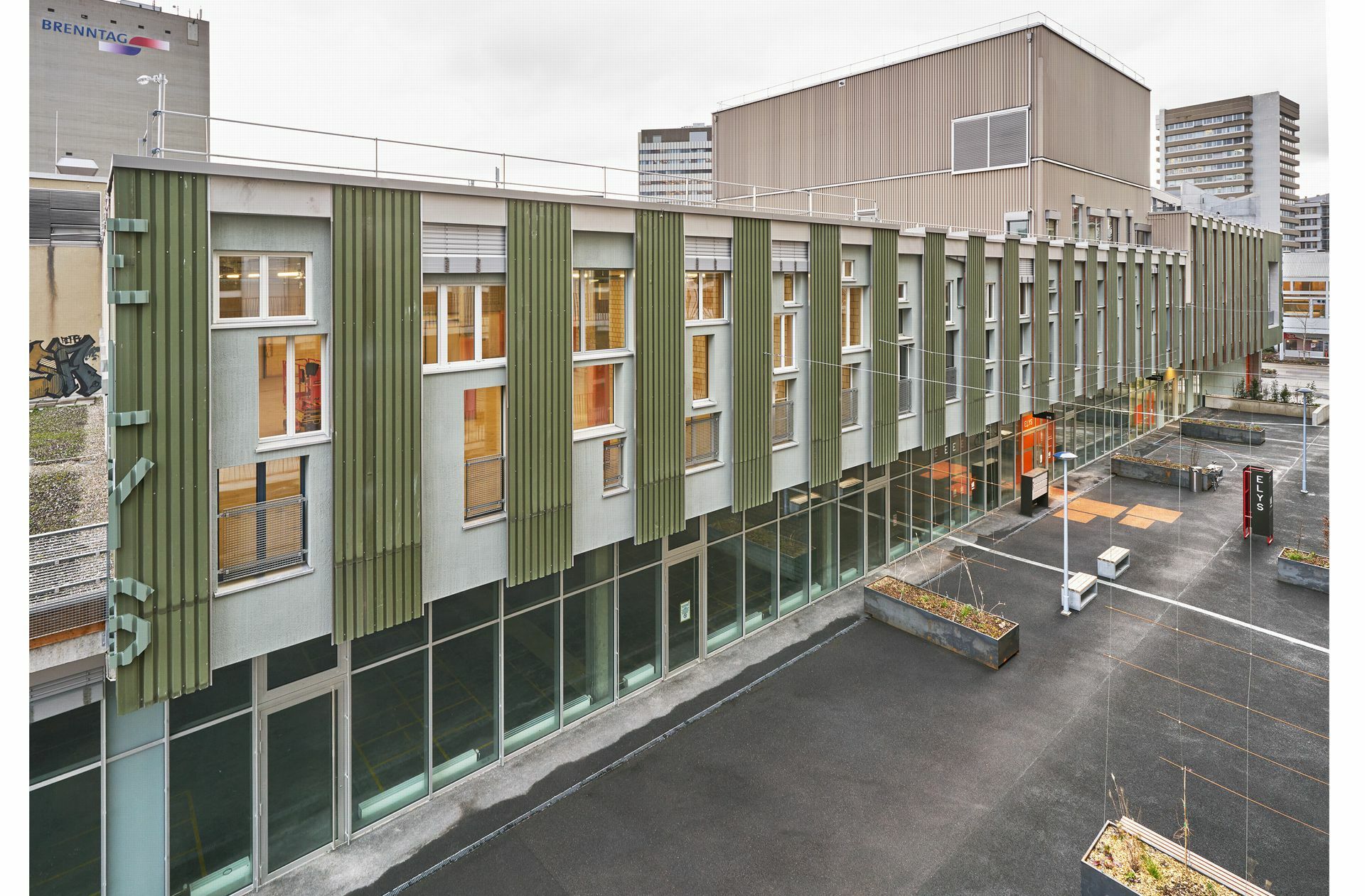 Hier noch eine Ansicht des Kultur- & Gewerbegebäudes „ELYS“ in Basel: Bei der Umnutzung des coop Verteilzentrums in Basel zu einem Gewerbe- und Kulturhaus wurden rund 1000 Quadratmeter neue Fassadenfläche vorrangig aus wiederverwendetem Baumaterial erstellt. Für die Fassade wurden Holzelemente vorfabriziert, die so konzipiert wurden, dass rund 200 Fenster in unterschiedlichsten Größen und Formen eingefügt werden konnten und . . .