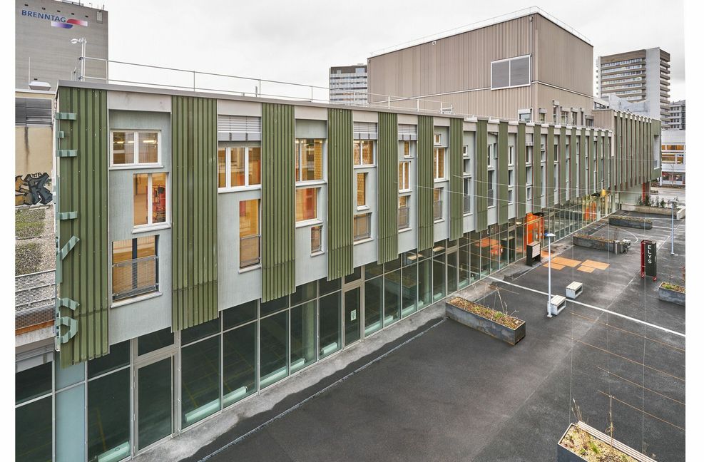 Hier noch eine Ansicht des Kultur- & Gewerbegebäudes „ELYS“ in Basel: Bei der Umnutzung des coop Verteilzentrums in Basel zu einem Gewerbe- und Kulturhaus wurden rund 1000 Quadratmeter neue Fassadenfläche vorrangig aus wiederverwendetem Baumaterial erstellt. Für die Fassade wurden Holzelemente vorfabriziert, die so konzipiert wurden, dass rund 200 Fenster in unterschiedlichsten Größen und Formen eingefügt werden konnten und . . .