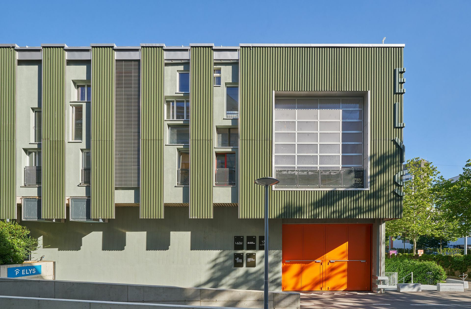 . . . die Bauteiljägerinnen und -jäger fanden  nur 50 Meter Luftlinie entfernt gebrauchte Fassadenbleche. Die Verwendung dieser Fenster mit den verschiedensten Größen, Farben und Materialien ergibt ein interessantes  Fassadenbild, das durch die einheitlichen Blechelemente rhythmisiert wird.