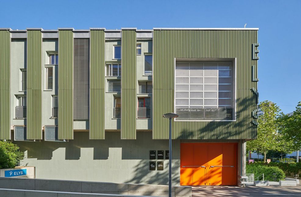 . . . die Bauteiljägerinnen und -jäger fanden  nur 50 Meter Luftlinie entfernt gebrauchte Fassadenbleche. Die Verwendung dieser Fenster mit den verschiedensten Größen, Farben und Materialien ergibt ein interessantes  Fassadenbild, das durch die einheitlichen Blechelemente rhythmisiert wird.