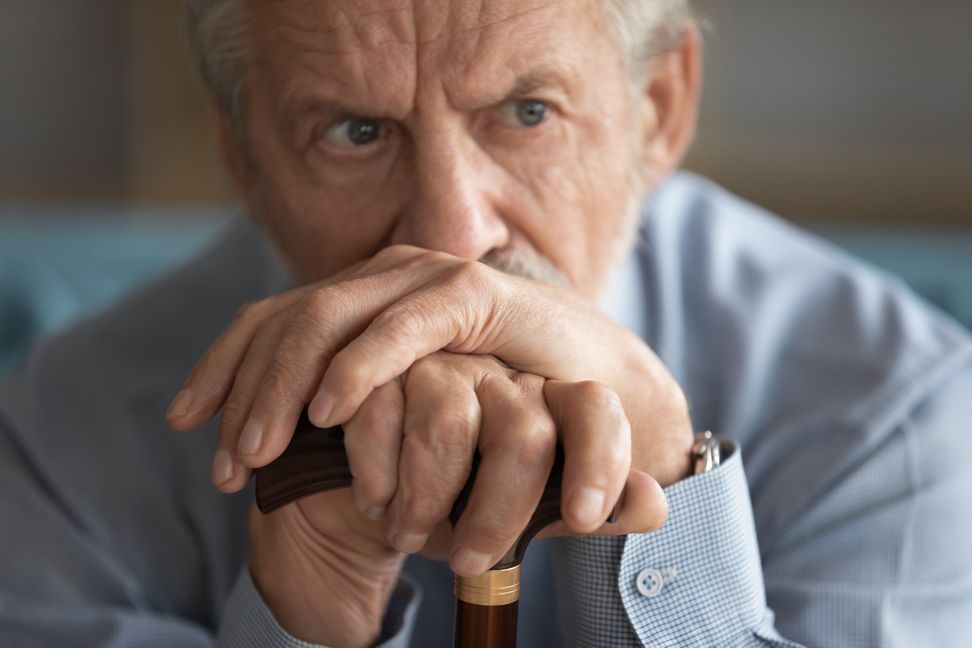 Close up of sad distressed mature 60s man with walking stick look in distance thinking pondering, upset lonely old male with wooden cane lost in thoughts yearning or missing, elderly solitude concept