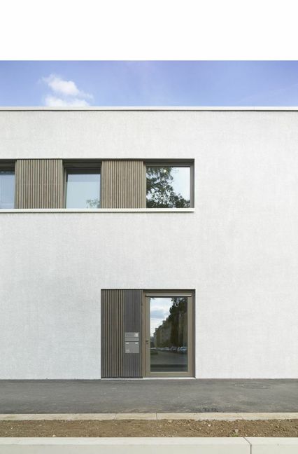 Grobkörniger Putz, grau lasierte Fensterläden und -rahmen.