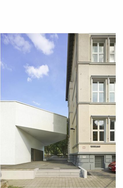 Von der Straßenseite aus betrachtet wirkt die eingeschnittene Dachebene wie eine architektonische Geste des Respekts gegenüber dem Gebäude aus dem Jahr 1901. Beide Baukörper bleiben Solitäre.