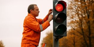 Ein Straßenbaumitarbeiter montiert eine Ampel.