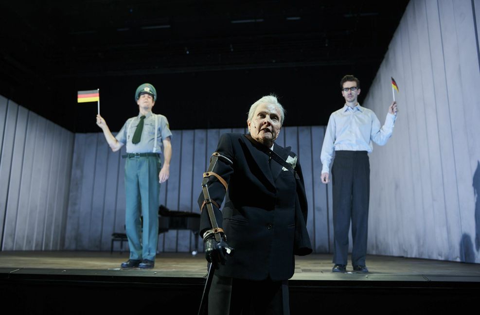 Gabriele Hintermaier spielt in der Inszenierung von Burkhard C. Kosminski den ehemaligen Richter und berichtet von der Verhandlung. Im Hintergrund Felix Strobel als Polizist (li.) und rechts Marco Massafra als Lehrer.