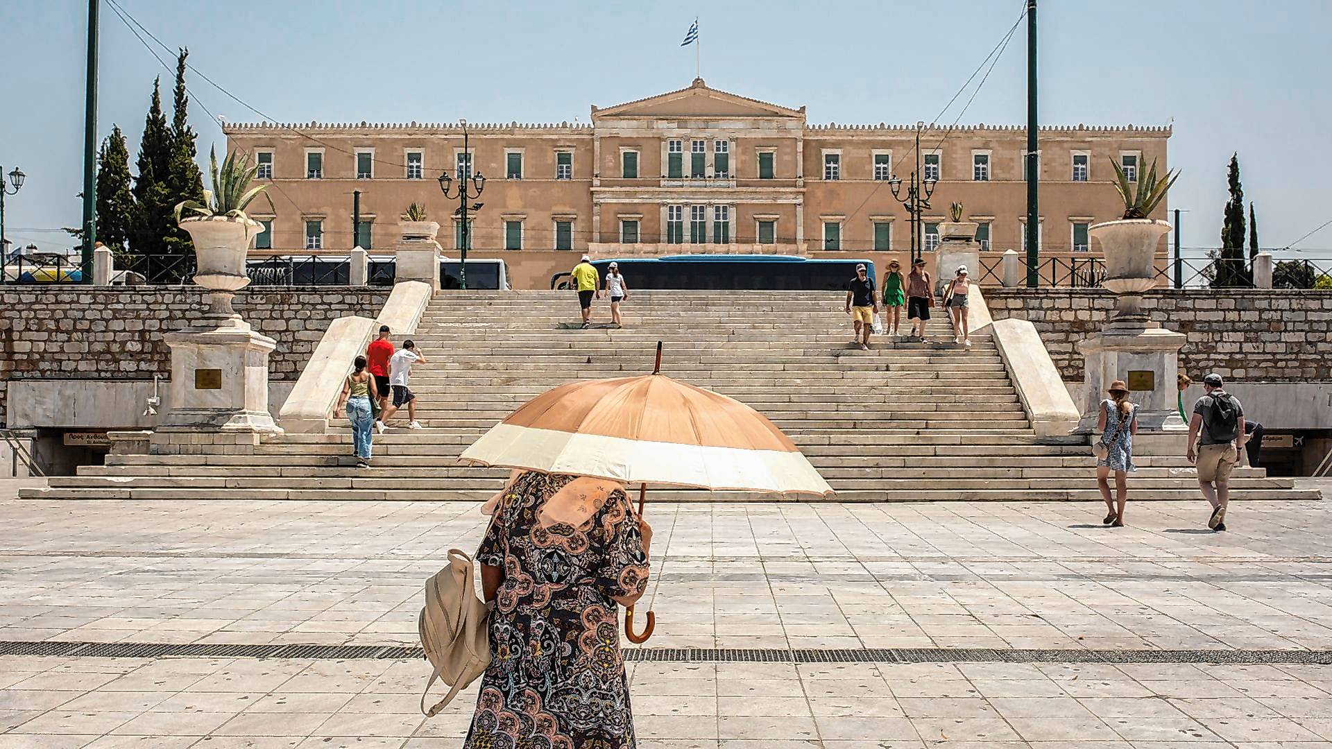 Eine Frau schützt sich mit einem Sonnenschirm  auf dem Syntagma-Platz in Athen vor der Sonne.