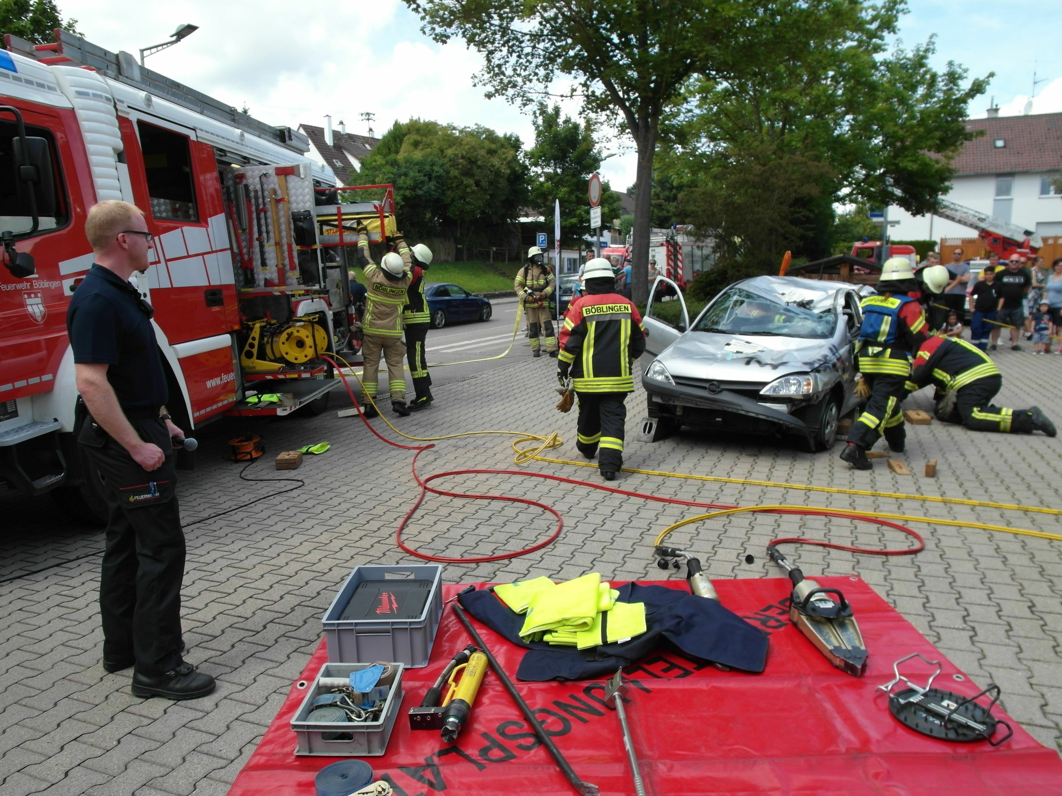 Der Dagersheimer Abteilungskommandant Frank Dietzel (links)
moderiert die Schauübung, bei der die Rettung eines Verunglückten aus
einem Auto simuliert wird.   Bild: Staber