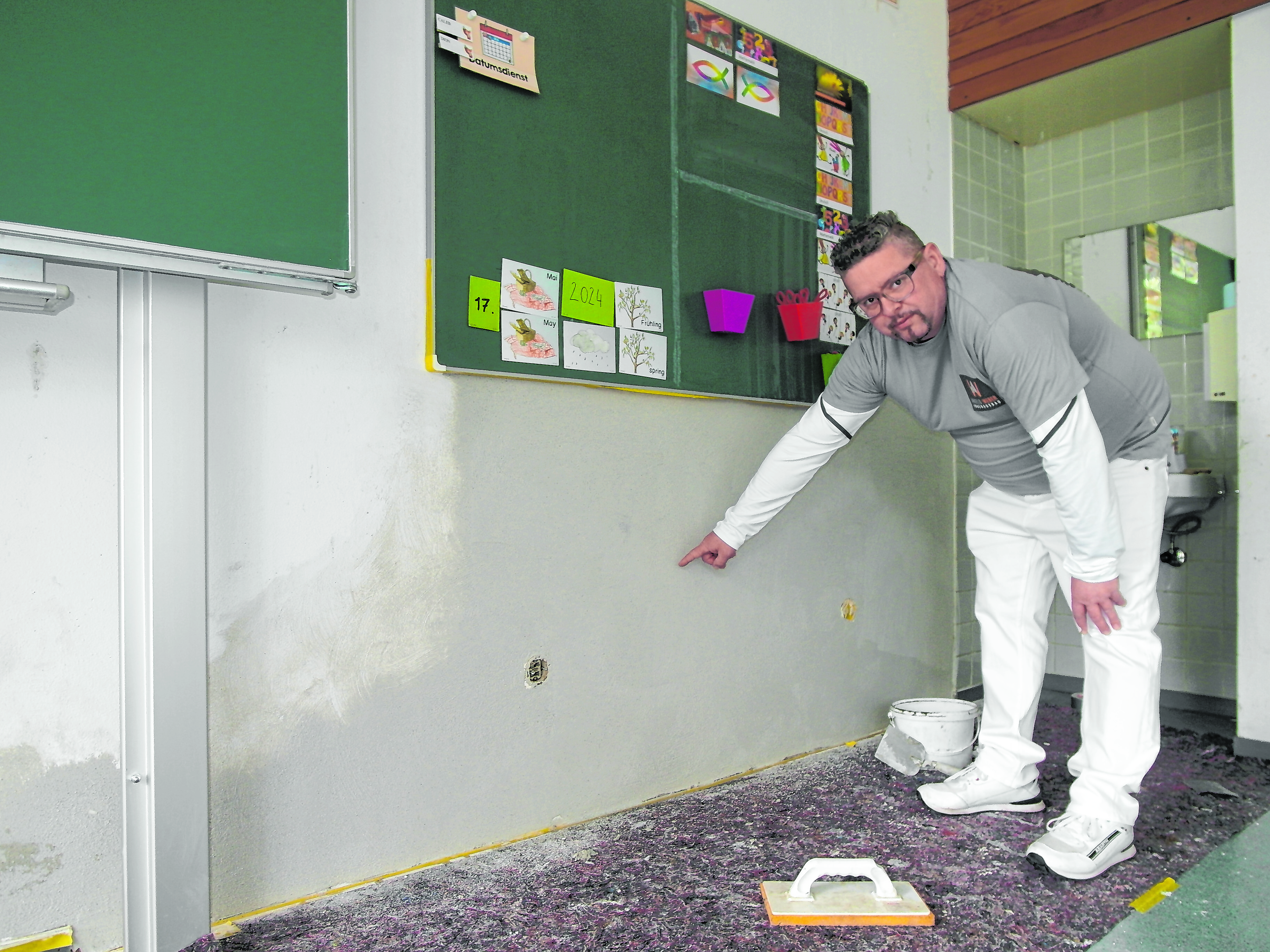 Bauleiter Arthur Weber zeigt auf die Stelle, wo in einem Klassenzimmer der Böblinger Eichendorffschule ein Loch in einer Wand repariert worden ist, die wegen eines Wasserschadens hatte aufgestemmt werden müssen - dort lag zuvor ein Stromkabel frei.