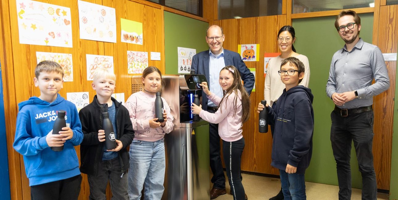 Oberbürgermeister Dr. Bernd Vöhringer (Mitte), Schulleiterin Ly-Ly Do und Timo Plankenhorn, Leiter des Amtes für Bildung und Betreuung, testen mit Schülerinnen und Schülern der dritten und vierten Klassen der Grundschule Hinterweil den neuen Wasserspender.