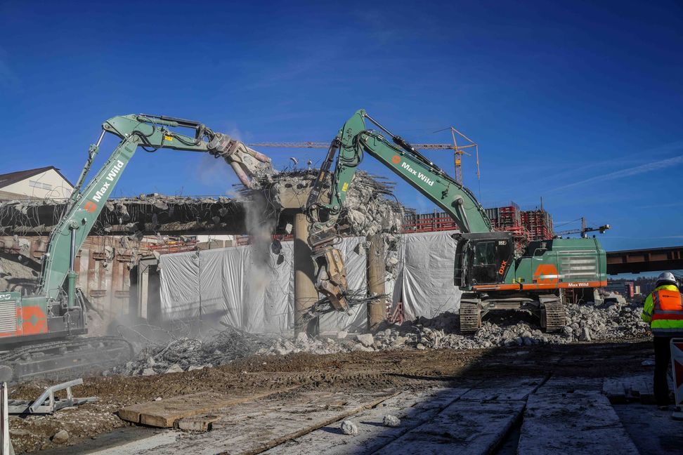 Bagger mit unterschiedlichen Werkzeugen bearbeiten die Brücke.