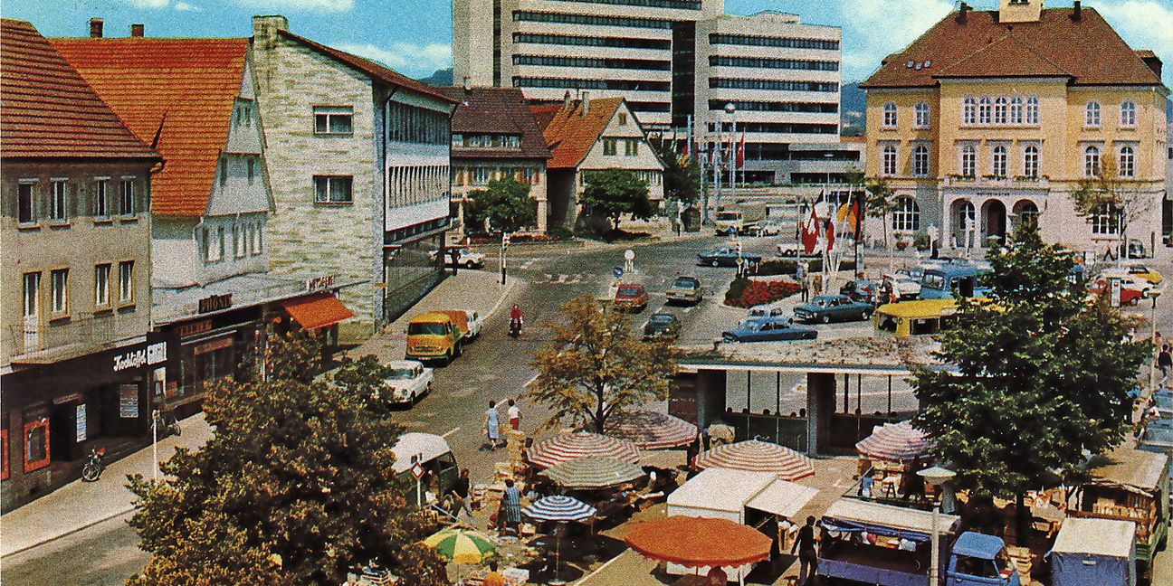 Das Foto aus dem Jahr 1975 zeigt das neue Rathaus hinter seinem Vorgänger aus dem Jahr 1845. Noch stehen der Bauernhof Essig, das Geschäft von Eugen Klein und die alte Kreissparkasse am Platz, der noch als Busbahnhof genutzt wird.