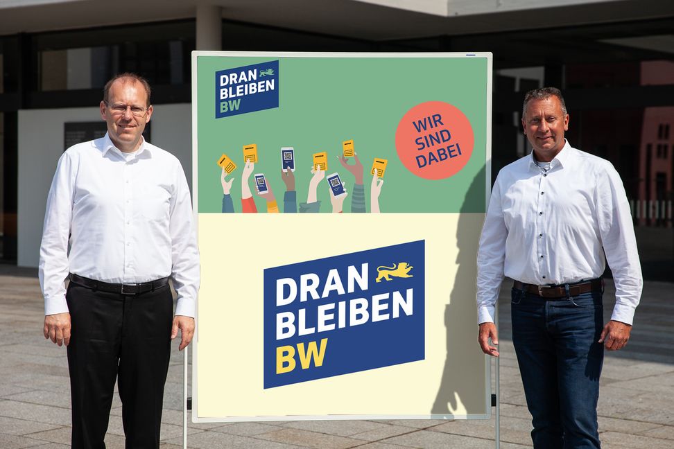 Sindelfingens Oberbürgermeister Dr. Bernd Vöhringer (links) und Roland Narr vom städtischen Krisenstab präsentieren das Logo der Impf-Kampagne #dranbleibenBW.              Bild: Stadt Sindelfingen / z