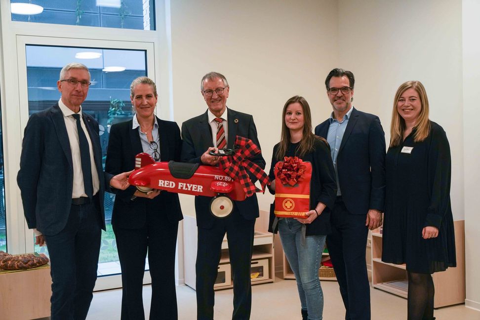 Landrat Roland Bernhard (Mitte), KVSW-Geschäftsführer Alexander Schmidtke (links) und Ressortleiterin Personal des KVSW, Kathrin Bahnmüller (Zweite von links), überreichen Geschenke zur Einweihung an das Team von 
Educcare: Regionalmanagerin Sandra Bauer, Gründer und Geschäftsführer Markus Bracht und Einrichtungsleiterin Lynn Pleuß (von rechts).
