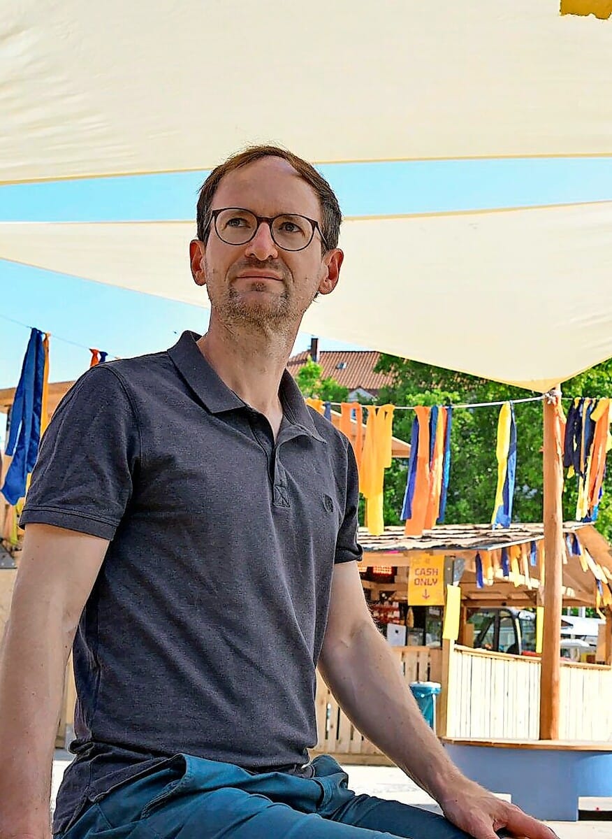 Bastian Schröter von der Hochschule für Technik beschäftigt sich mit dem Kühlbedarf Stuttgarts. Hier sitzt er unter einem Sonnensegel am Marienplatz.