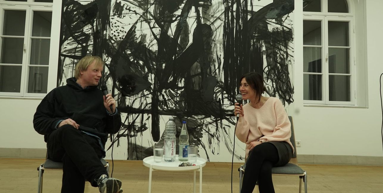 Hannah Eckstein im Gespräch mit Chris Succo vor dem Succo-Bild „The Unknown Known“.