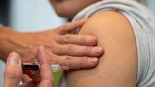 Eine Gynäkologin setzt bei der HPV-Impfung in einer Frauenarztpraxis eine Injektion in den Oberarm einer Jugendlichen.