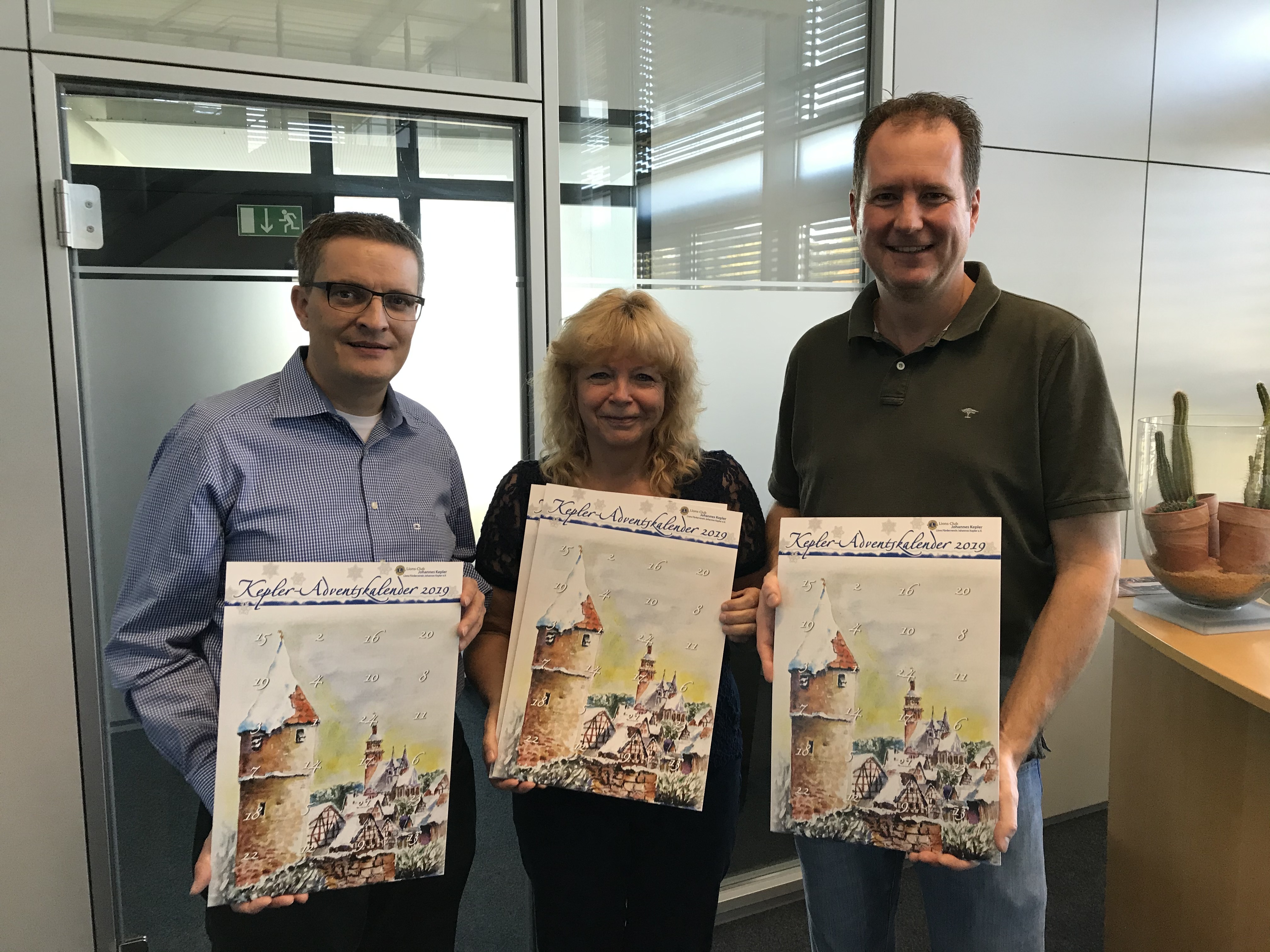 Präsentieren den Adventskalender:  Matthias Rapp, Eveline Fiedler und Roman Frik, alles vom Lions Club Johannes Kepler.´(von links).
