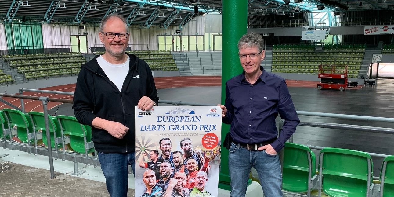 Uwe Dieterich (links) und Claus Regelmann präsentieren das Plakat des European Darts Grand Prix. Am Wochenende platzt der Glaspalast aus allen Nähten. Bild: Holzapfel