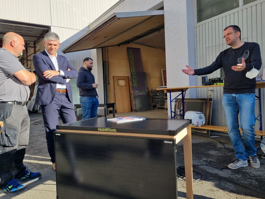 Vergangenen Sommer haben Schreiner Markus Ruzicka (von links), Bürgermeister Ioannis Delakos, Ruzicka-Mitarbeiter Christopher Neurauter und Ingenieur Guido Burger den Holzgerlinger Solartisch präsentiert. Den Kauf eines solchen bezuschusst die Stadt künftig ebenso wie die Installation eines PV-Balkonkraftwerks. Bild: Hamann