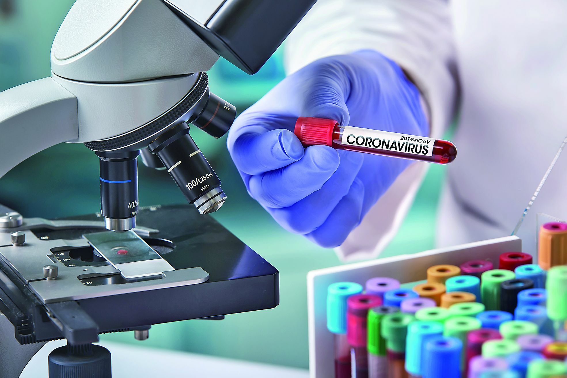 microbiologist with a tube of blood contaminated by Coronavirus and a sample of it analyzed under a microscope / doctor in the laboratory with a blood tube for analysis and sampling of Coronavirus under the microscope