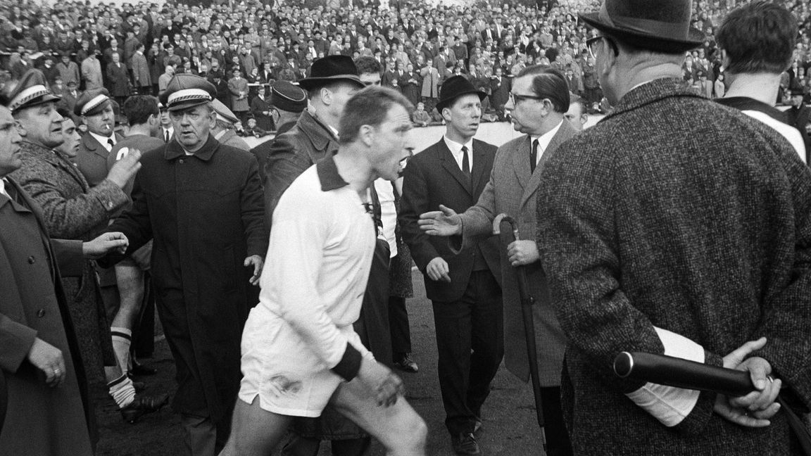 Man hört das Fluchen förmlich aus dem Bild heraus: Karlheinz Mozin (SW Essen, Mi.)) wütend zwischen den Ordnern in den 1960ern bei einem Spiel der Regionalliga West.