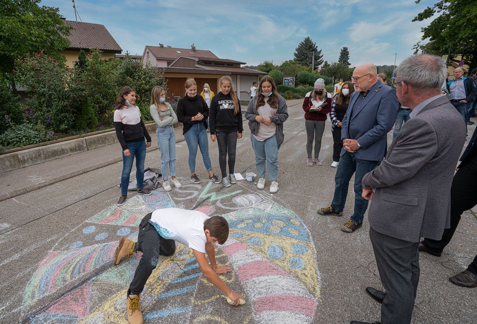 Verkehrsminister Winfried Hermann sprach, im Beisein von Bürgermeister Clemens Götz, mit Schülern, die auf der Schulstraße mit Kreide gezeichnet hatten.  Bild: Richter