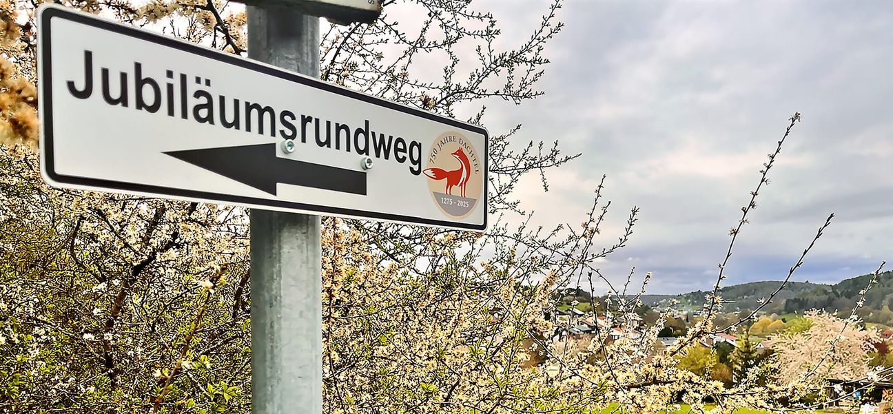 Entlang des Weges sind Schilder mit dem Jubiläumslogo Dachtels aufgestellt. Bild: z